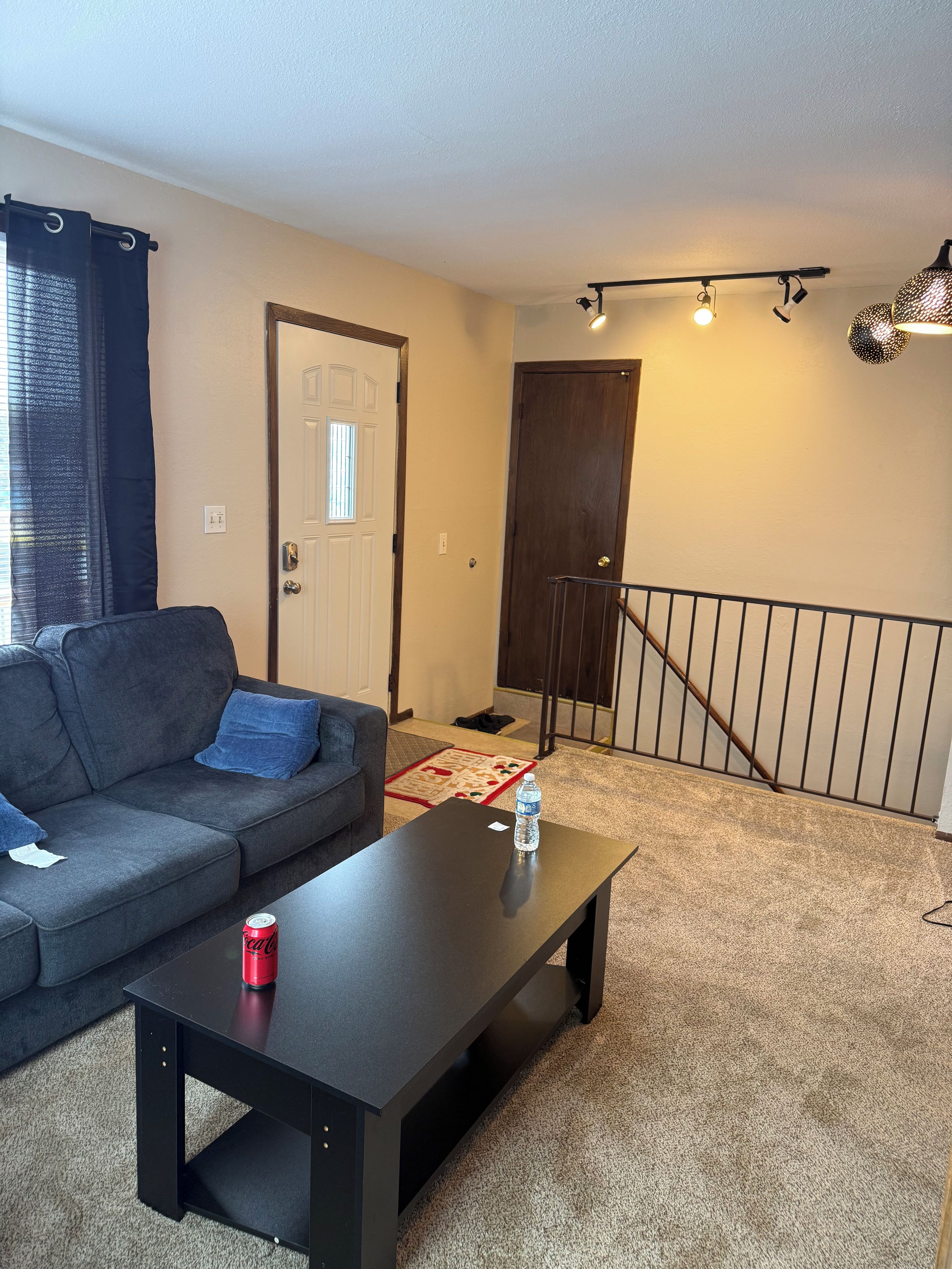 A living room with a sofa, a coffee table, a door, and a staircase.
