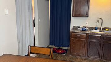 Une cuisine de taille réduite comprenant une table et des chaises, un évier et un meuble de rangement.