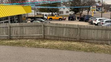 Un parking rempli de voitures, un bâtiment jaune et une clôture en bois.