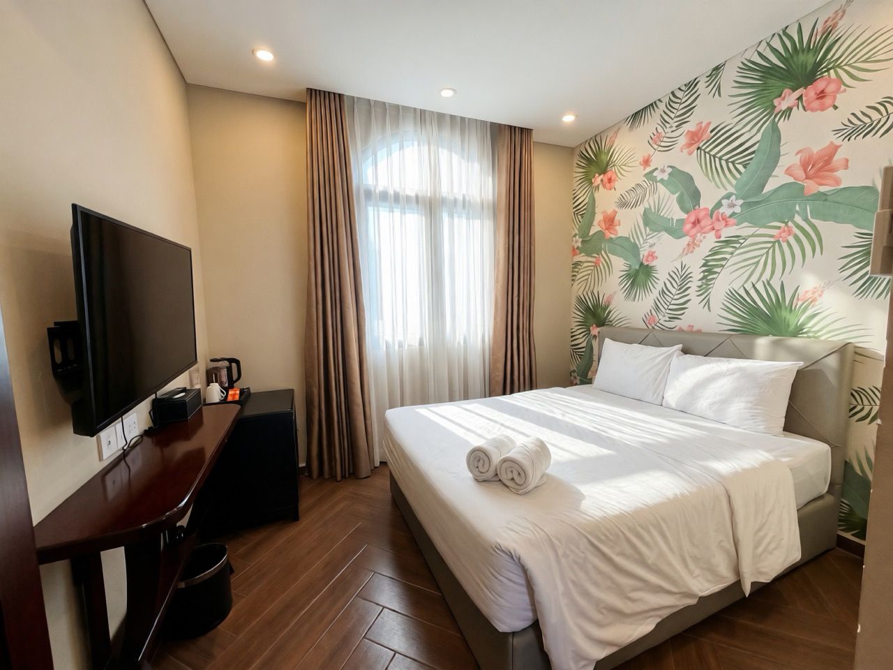 A hotel room with a bed, a TV, a desk, and a coffee maker.