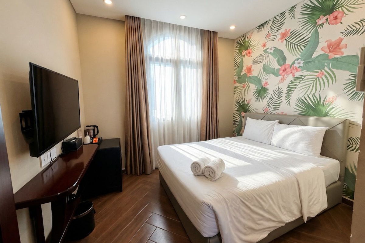Una habitación de hotel con cama, televisión, escritorio y cafetera.