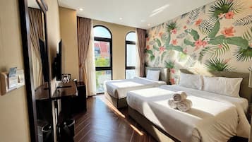 A hotel room with two beds, a TV, a desk, and a window with curtains.