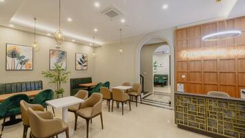 A restaurant interior with a reception desk, seating area, and wall art.