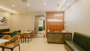 A restaurant interior with a reception desk, seating area, and a green sofa.