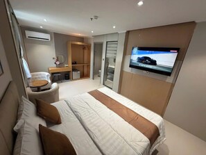 Una habitación de hotel moderna con cama, televisión, escritorio y silla.