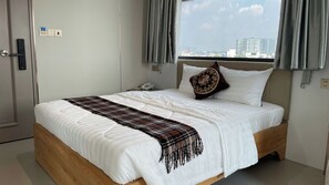 Una habitación de hotel con una cama, un teléfono y una ventana con cortinas.