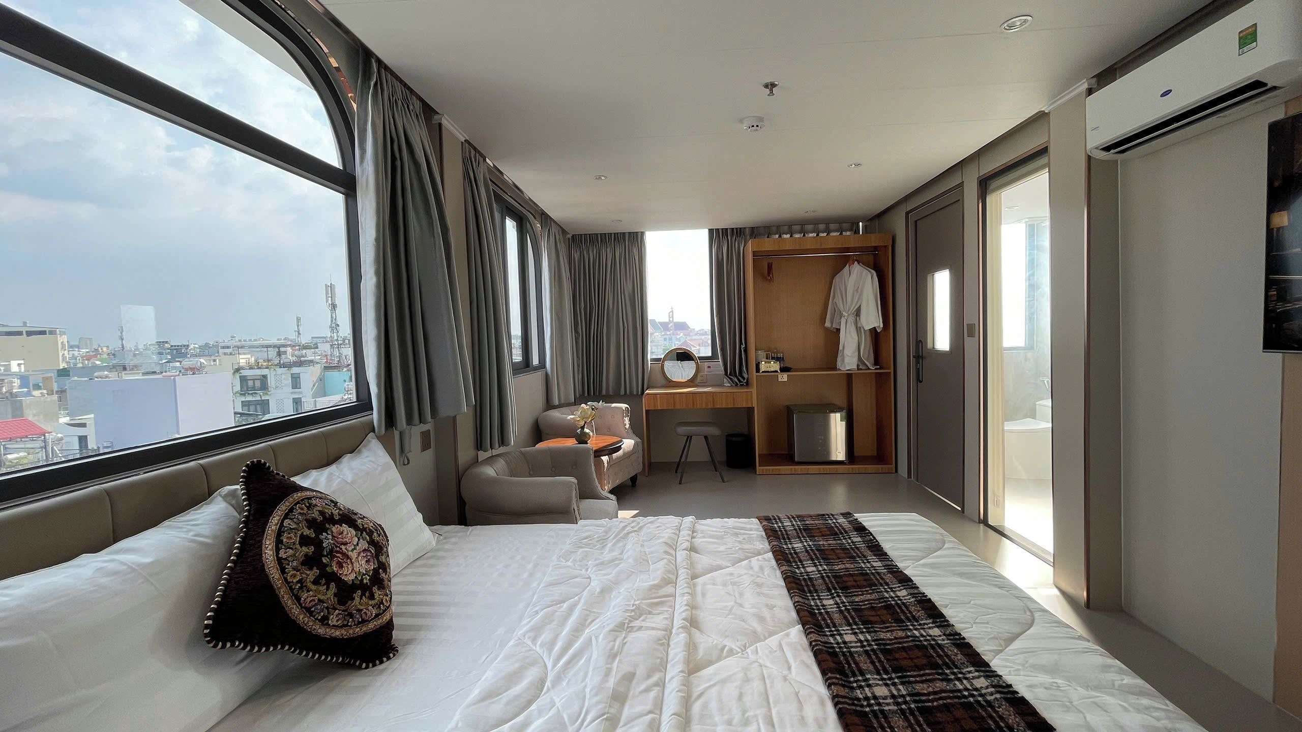 Une chambre d’hôtel avec un grand lit, un bureau, une chaise et une armoire.
