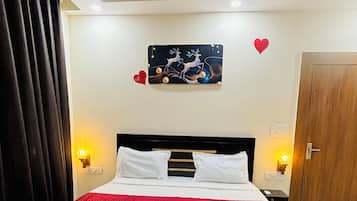 A hotel room with a bed, a red rug, a wall-mounted picture, and a door.
