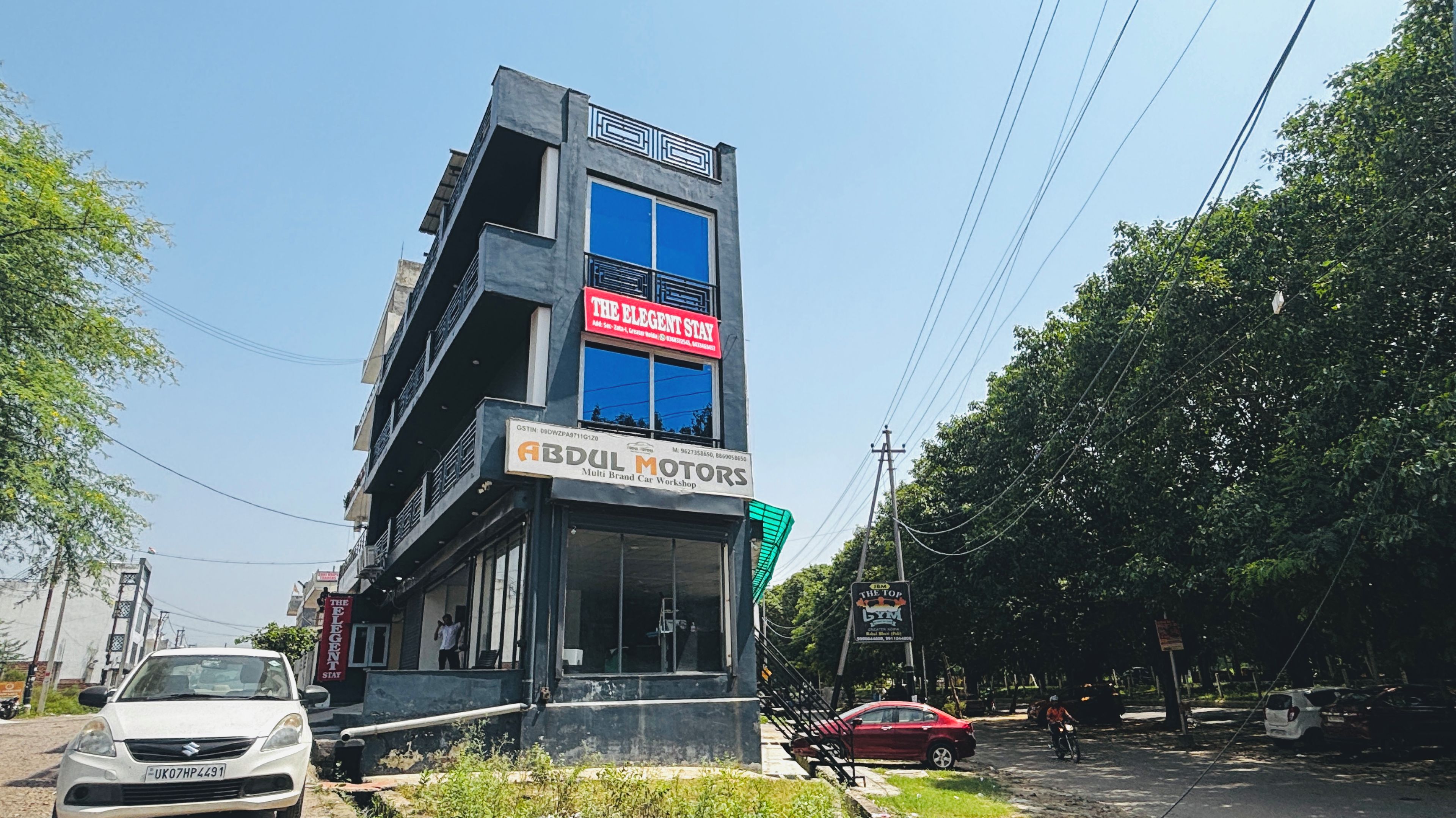 A multi-story building with signage for 'The Elegant Stay' and 'ABDUL MOTORS'.