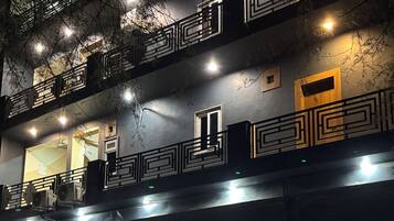 Un edificio de varios pisos con balcones, unidades de aire acondicionado y un portón de garaje cerrado.