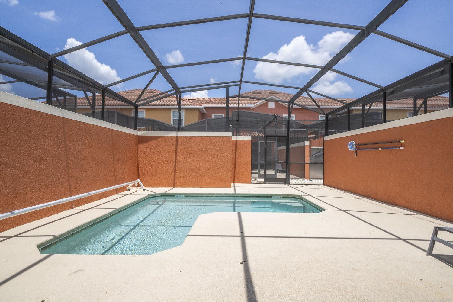 Une piscine extérieure couverte, dotée d’un toit en verre, entourée de murs et offrant une vue sur des immeubles d’habitation en arrière-plan.