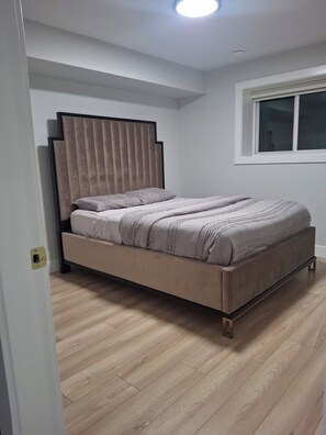 A bedroom with a bed, a window, and wooden flooring. - Brand new 2 bed room 1private washroom (Delta)