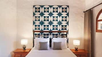 Una habitación de hotel con un cabecero estampado, una cama con dos almohadas y lámparas de noche.