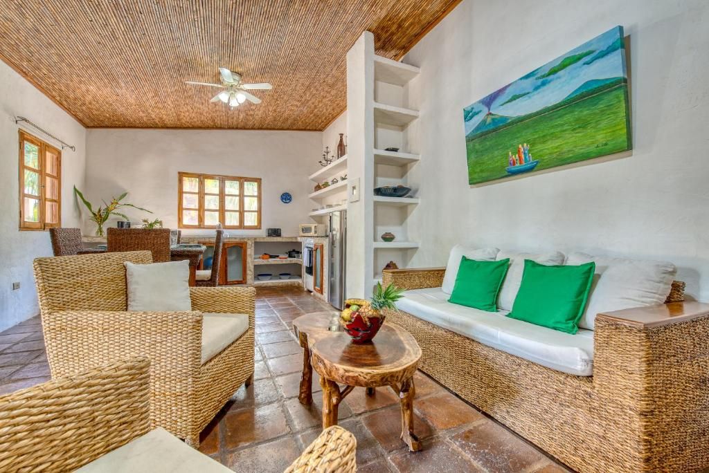 A spacious living area with wicker furniture, a ceiling fan, and a painting of a landscape.