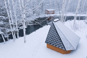 Paisaje nevado con una estructura de madera y un techo hexagonal.