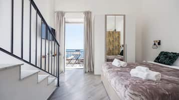 Ein Schlafzimmer mit einem großen Bett, einem Balkon mit Tisch und Stühlen und Blick auf das Meer.