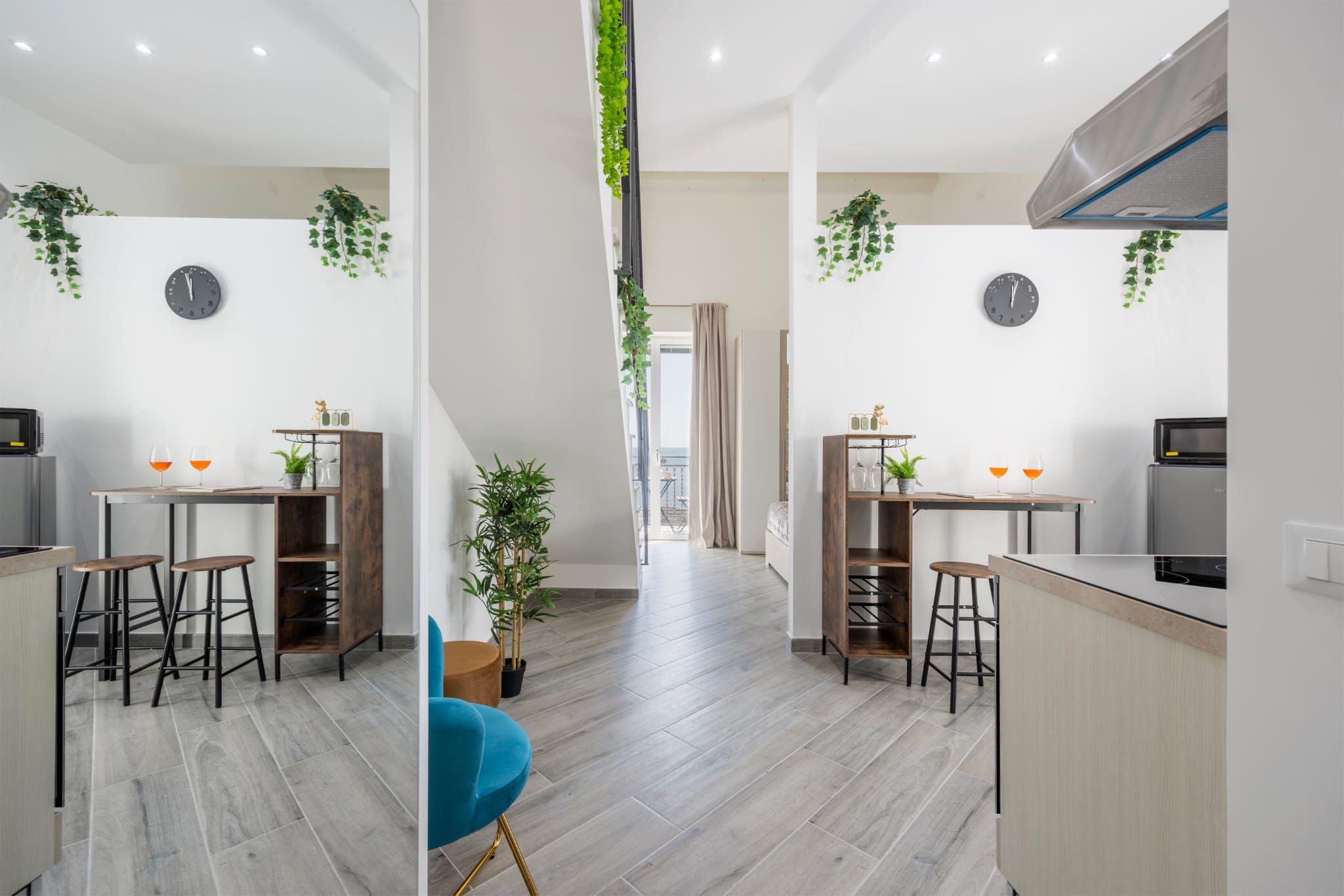 A modern kitchen with a central island, bar stools, and a view of the balcony.