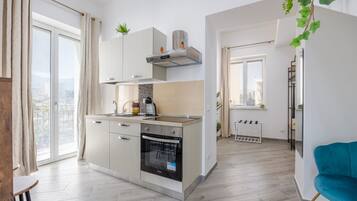 A modern kitchen with a built-in oven, a window, and a view of the city.