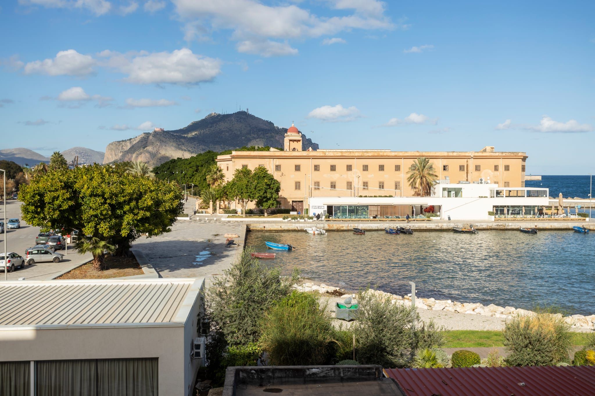A coastal building with a view of the sea and a mountain in the background.