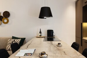 A modern dining area with a marble table, black pendant light, and a coffee machine. - SANT'ERASMO LUXURY HOME (Palermo)