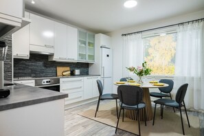 Una cucina moderna con mobili bianchi, un piano di lavoro nero e un'area pranzo con un tavolo rotondo e sedie.