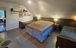 Un dormitorio con una cama grande, dos mesitas de noche, un tocador, un aparador, una ventana con cortinas y una obra de arte en la pared.
