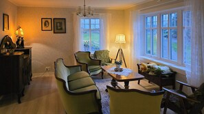 Un comedor con una mesa, sillas, una lámpara y vistas al exterior a través de ventanas amplias.