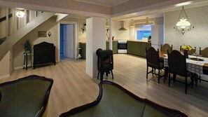 Amplia sala de estar con mesa de comedor, sillas, una escalera y una cocina al fondo.