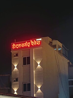 A building with a sign in a foreign language, indicating a hotel. - HOTEL NARMADA PALACE (Ujjain)