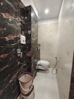 A bathroom with a marble wall, a toilet, a shower, and a basin. - HOTEL NARMADA PALACE (Ujjain)