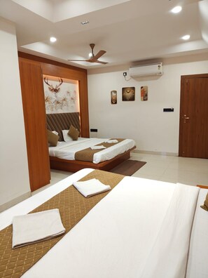 A hotel room with a bed, a ceiling fan, an air conditioning unit, and a wooden door. - HOTEL NARMADA PALACE (Ujjain)