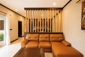 A modern living room with a leather sofa, a wooden coffee table, and a decorative partition with vertical slats. - Phuket Rawai Private Pool Villa with Garden - 2BR (Tambon Rawai)