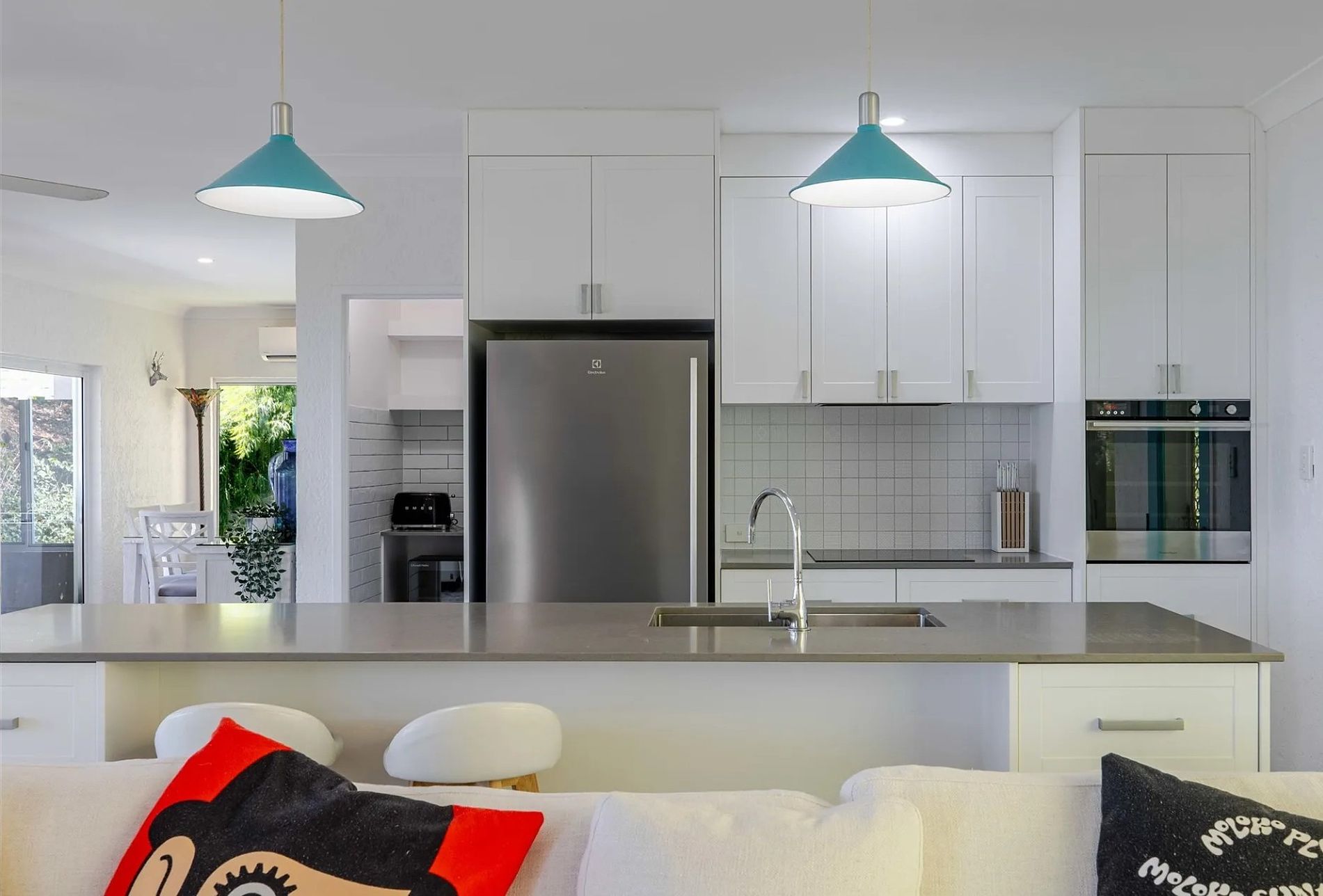 Kitchen : The kitchen includes a wide island bench, full-size fridge, oven and cooktop, with open connection to the lounge and dining areas.