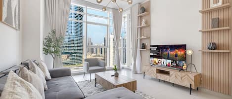 A modern living room with a large flat-screen TV, a sofa set, a coffee table, and a decorative chandelier.