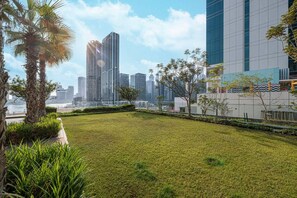 A grassy courtyard with a view of high-rise buildings. - Deluxe Nine Tower Suites By Hostiva - Burj View (Dubai)