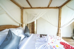 Een kamer met een bed, een houten hoofdbord en een hemelbed.