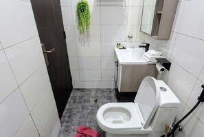 A modern bathroom with a toilet, sink, and mirror. - Modern luxury studio Airbnb (Kampala)
