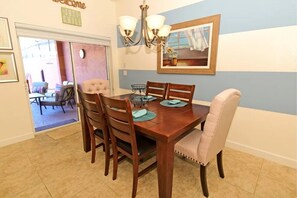 Un comedor con mesa de madera, seis sillas y una lámpara de araña.