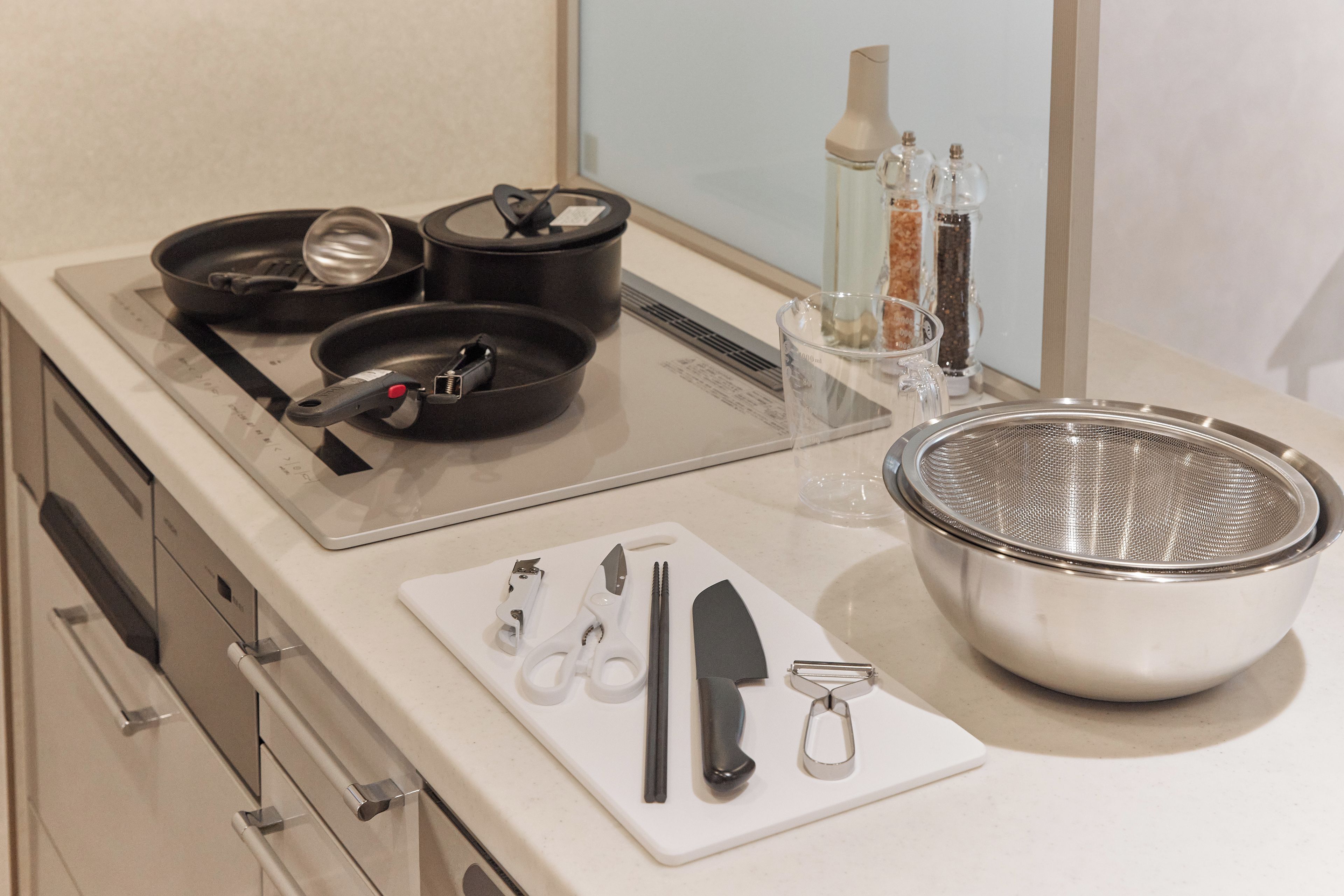 A kitchen with a stove, pots, a colander, and a cutting board with utensils.