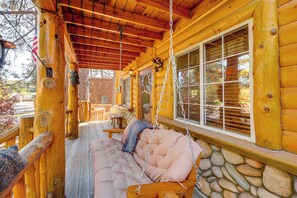 Eine Holzhütte mit Veranda, Schaukel und einer Steinmauer.