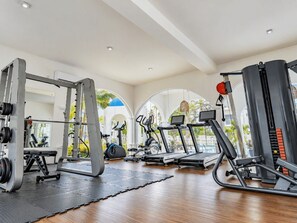 Ein Fitnessstudio mit Cardiogeräten, Gewichtstrainern und einer Spiegelwand.