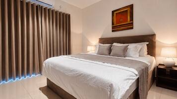 Une chambre d’hôtel moderne avec un grand lit, une table de chevet avec une lampe, un climatiseur fixé au mur et une fenêtre avec des rideaux.