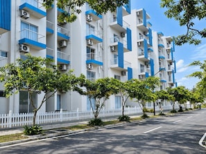 A multi-story residential building with balconies, air conditioning units, and a white picket fence. - Santorini Transit Apartment Negombo (Negombo)
