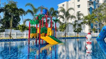 A swimming pool with a play structure and palm trees.