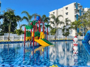 Ein Schwimmbecken mit Spielgerüst und Palmen.
