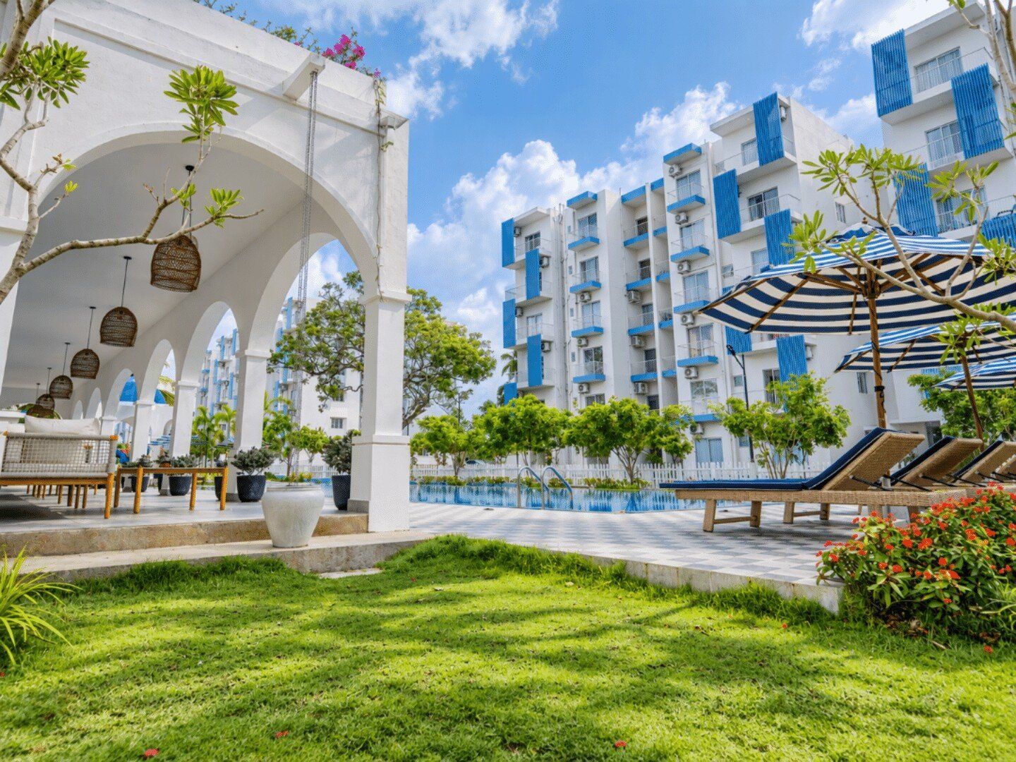 A hotel courtyard with a pool, outdoor seating, and a covered area with umbrellas.
