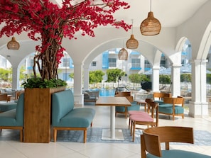 A spacious outdoor seating area with a large tree and hanging lights, overlooking a pool and buildings. - Santorini Transit Apartment Negombo (Negombo)