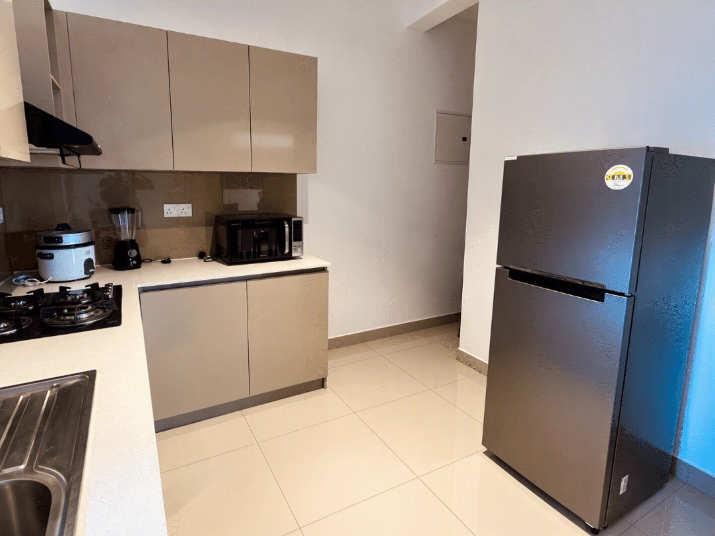 Een moderne keuken met een zwarte koelkast, een kookplaat, een magnetron en een blender op het aanrecht.