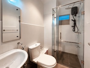 A modern bathroom with a glass-enclosed shower, a white toilet, and a sink. - Santorini Transit Apartment Negombo (Negombo)