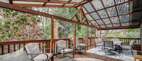 A covered outdoor seating area with wooden furniture and a metal table.